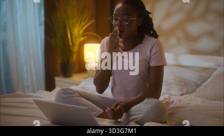 Verschlafene müde afroamerikanische Frau Studentin weibliches Mädchen, das Laptop arbeitet, Computer schreiben im Internet Hausaufgaben schreiben Notizen Bildung Gähnen Stockfoto