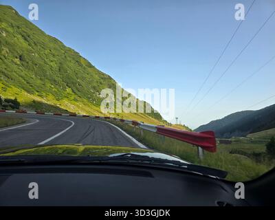 Eine gewundene Bergstraße mit scharfen Kurven, die von roten und weißen Leitplanken begrenzt wird. Stockfoto