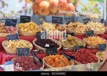 Bunte getrocknete Früchte in Körben an einem Marktstand, mit Tafeletiketten und Fruchtscheiben. Stockfoto