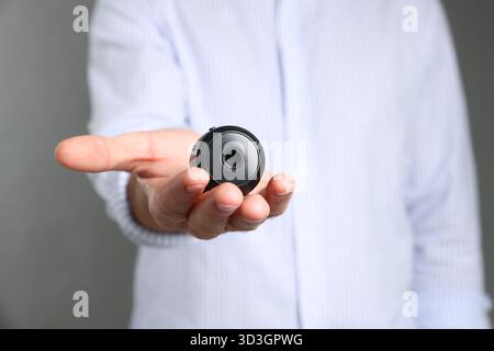 Mann mit versteckter Spionageskamera auf grauem Hintergrund, Nahaufnahme Stockfoto