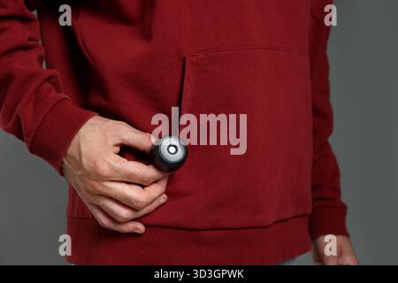 Mann mit versteckter Spionageskamera auf grauem Hintergrund, Nahaufnahme Stockfoto