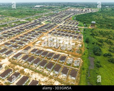 Blick aus der Vogelperspektive auf die Häuserreihen im Bau, mit ihren braunen Dächern, die im Kontrast zur grünen Umgebung stehen, Abuja, Nigeria. Stockfoto