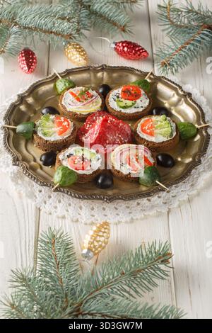 Nahaufnahme der Silvester-Sandwiches mit Frischkäse und Gemüse in Form von Weihnachtskugeln auf einem Teller auf einem Tisch. Vertikal Stockfoto