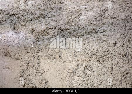 Detaillierte Nahaufnahme der groben trockenen Sandstruktur im Freien unter natürlichem Tageslicht, mit rauer körniger Oberfläche und subtilen Farbvariationen. Stockfoto