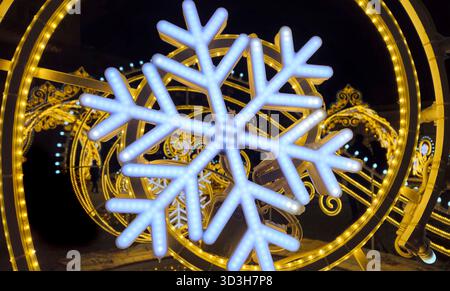 Wunderschöne glühende Weihnachten- und Neujahrsdekoration mit großen abstrakten Schneeflocken auf der Abendstraße Stockfoto