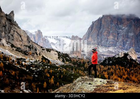 Eine weibliche Touristin, die steht und die spektakuläre Herbst-Panoramasicht des ikonischen Giau-Passes in den schönen Dolomiten, Italien, genießt. Stockfoto