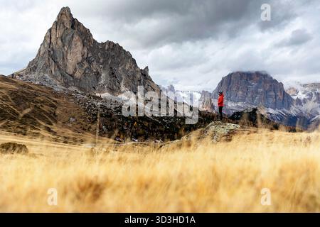 Eine weibliche Touristin, die steht und die spektakuläre Herbst-Panoramasicht des ikonischen Giau-Passes in den schönen Dolomiten, Italien, genießt. Stockfoto