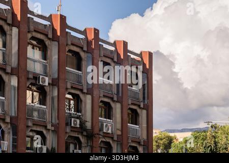 Äußere eines Wohngebäudes mit sich wiederholenden Balkonen und Klimaanlage gegen bewölkten Himmel. Stockfoto