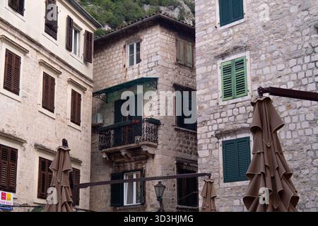 Historische Steinhäuser mit Holzläden und Balkonen auf einem traditionellen Altstadtplatz in Südeuropa. Stockfoto