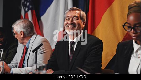 Mann, Fahnen und Porträt auf der Konferenz, glücklich und stolz mit der internationalen Delegation für den Frieden. Reifer Mensch, Politiker und globaler Führer Stockfoto