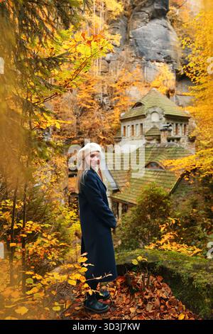 Gemütliche Herbstreiseszene mit einem Reisenden, der ein historisches Gebäude inmitten goldener Blätter bewundert. Stockfoto