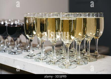 Essen, Nahaufnahme von Champagner- und Rotweingläsern für eine Feier, Party oder Catering-Veranstaltung auf einer Marmortheke Stockfoto