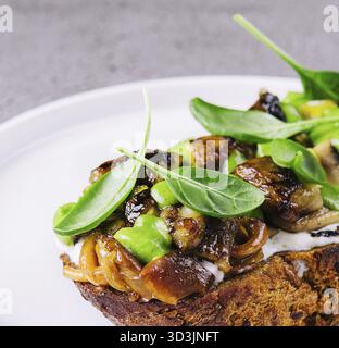 Essen, Toast mit gebratenen Stachelpilzen auf weißem Teller Stockfoto