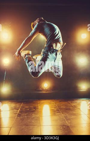 Junger Mann tanzt im Club mit Licht und Rauch. Warme Farben Stockfoto