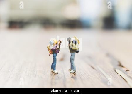 Miniatur-Backpacker, Touristen stehen auf Holz mit verschwommenem Hintergrund Stockfoto