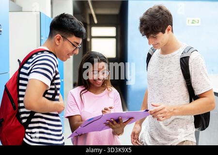 Glückliche, vielfältige Gruppe von Schülern, die zusammen im Flur studieren Stockfoto