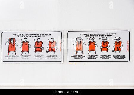Zwei Sicherheitshinweise zeigen die richtige Schwimmweste für Erwachsene und Kinder. Klare, Schritt-für-Schritt-Grafiken, die Sicherheit und Notfalleinsatz betonen Stockfoto