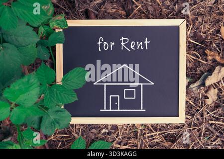 Tafel mit einem gezeichneten Haus und den Worten für Miete in der oberen rechten Ecke Stockfoto
