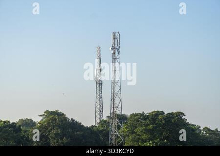 Zwei Telekommunikationstürme stehen hoch über den Bäumen vor klarem Himmel in Netrokona, Bangladesch Stockfoto