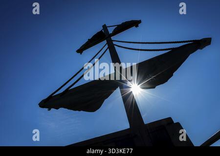 Silhouette eines Mastes eines Piratenschiffes mit der Mittagssonne über dem Hintergrund des blauen Himmels Stockfoto