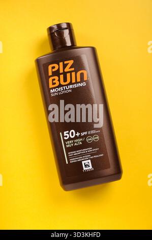 Flasche Piz Buin Factor 50 SPFfeuchtigkeitsspendende Sonnenbräunungslotion auf gelbem Hintergrund mit Kopierraum von oben Stockfoto