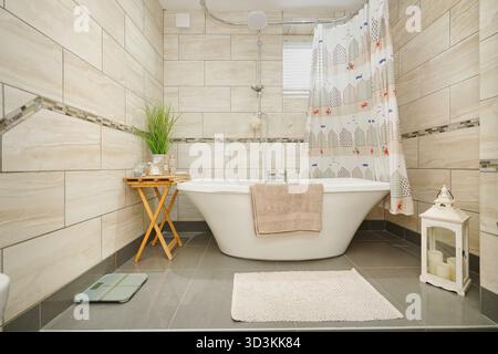 Entspannender Badezimmerbereich mit eleganter Badewanne und heller Einrichtung, ideal für Selbstpflegemomente in einem modernen Zuhause Stockfoto