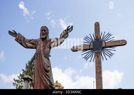 Majestätische Jesus-Statue mit ausgebreiteten Armen neben dem reich verzierten Kreuz Stockfoto