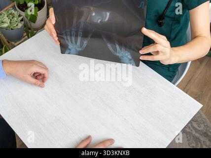 Ärztin, die den Röntgenfilm der Hände des Patienten untersucht Stockfoto
