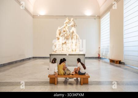 NEAPEL, ITALIEN – AUGUST 2025: Eine Familie sitzt auf einer Bank und betrachtet die kolossale Marmorstatue Farnese Bulle im Archäologischen Museum von Neapel - Stockfoto