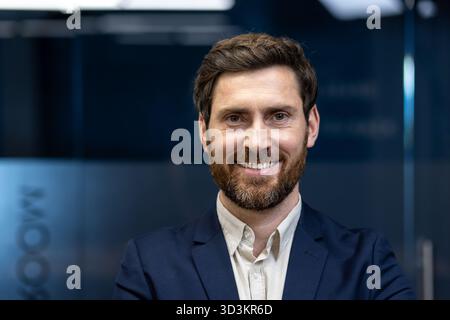 Nahporträt eines jungen lächelnden und erfolgreichen Geschäftsmannes im Büro mit Blick auf die Kamera. Stockfoto