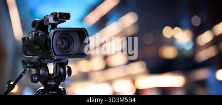 Videokamera auf dem Ständer vor verschwommenem Hintergrund. Bannerdesign Stockfoto