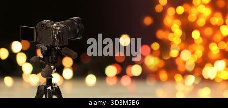 Professionelle Kamera vor verschwommenem Hintergrund mit Bokeh-Lichtern. Bannerdesign Stockfoto