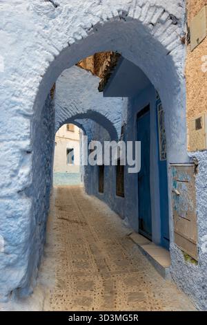 Ikonische Spitzbögen, die typisch arabische Architektur definieren, säumen die malerischen blauen Straßen von Chefchaouen, der blauen Stadt in Marokko. Die Szene wird aufgenommen Stockfoto