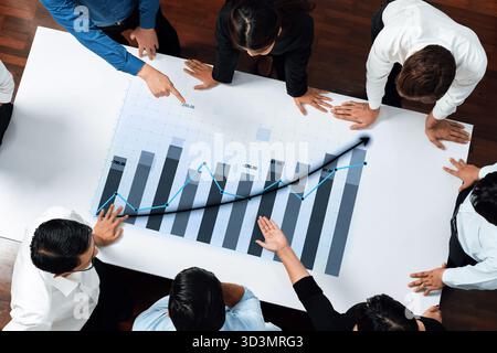 Während einer Strategiebesprechung arbeitet eine Gruppe von Fachleuten an einem Diagramm für das Unternehmenswachstum zusammen und hebt Teamarbeit und Datenanalyse in einem hervor Stockfoto