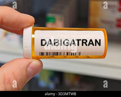 Orange Plastikbox von DABIGATRAN Tabletten auf einem Krankenhaus Apothekentisch verwendet, um Schlaganfall und Blutgerinnsel ein Antikoagulans zu verhindern. Apothekenlager Stockfoto