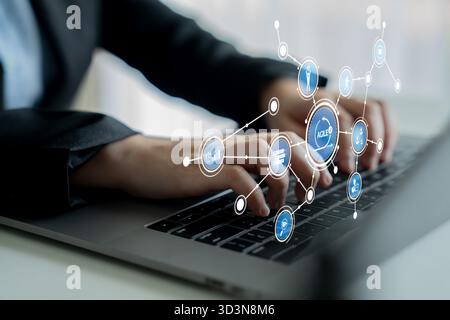 Ein Geschäftsmann verwendet eine Laptop-Tastatur, umgeben von digitalen Symbolen, die Technologie und Kommunikation symbolisieren. Das moderne Büro vermittelt Stockfoto