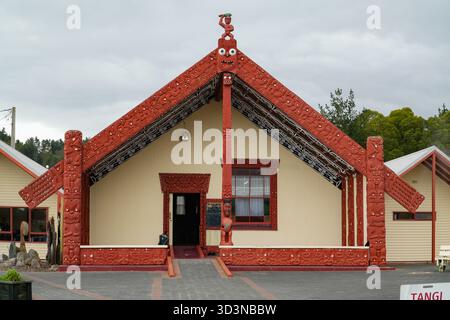 Wharenui. Blick von außen auf ein traditionelles Maori-Meeting-Haus mit kunstvollen roten Holzschnitzereien und kulturellen Motiven im Whakarewarewa Living Maori Vill Stockfoto