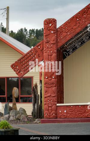 Māori geschnitzte Details eines Wharenui (Versammlungshauses) in Whakarewarewa, dem Living Māori Village, Rotorua, Neuseeland. Mit komplizierten roten Holzschnitzereien Stockfoto