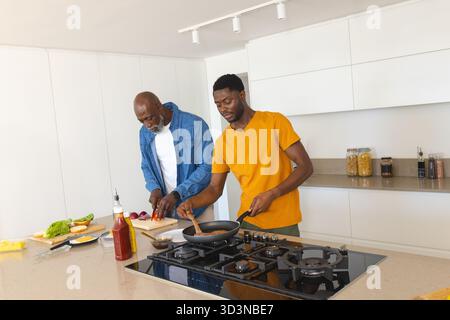 Wir kochen afroamerikanischen Vater und Sohn und bereiten in der modernen Küche Mahlzeiten zu, mit frischem Gemüse Stockfoto
