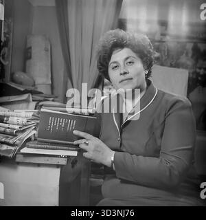 Ein Archivfoto aus dem Jahr 1981 aus der AIZ (Armature-Isolator Plant) in Sloviansk, ukrainische SSR. Eine weibliche Mitarbeiterin, Mitglied des Frauenrates (Zhensovet), posiert in ihrem Büro. Sie hält das offizielle Buch Material des XXVI Kongresses der KPdSU (1981). Dieses Buch war der Haupttext für politische Bildungsklassen. Ihr Schreibtisch ist voller Zeitungen. Dies fängt die ideologische Arbeit in einer sowjetischen Fabrik ein. Dies zeigt den Alltag im friedlichen Donbass vor dem Krieg. Stockfoto