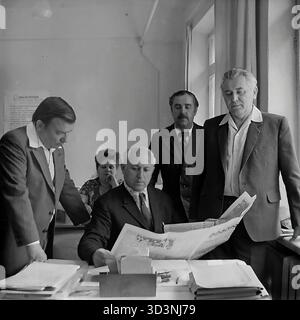 Ein Archivfoto aus dem Jahr 1981 zeigt eine Gruppe von Mitarbeitern der AIZ (Armature-Isolator Plant) in Sloviansk, ukrainische SSR. Fünf Kollegen (vier Männer und eine Frau) sind in einem Büro zu einem politischen Briefing versammelt. Ein leitender Angestellter, der an seinem Schreibtisch sitzt, liest einen artikel aus einer zentralsowjetischen Zeitung, wahrscheinlich "Prawda", während die anderen aufmerksam zuhören. Diese kollektive Lektüre der offiziellen Parteipresse war in der UdSSR eine gängige Praxis. Dies spiegelt die ideologische Seite des Arbeitsalltags im friedlichen Donbass vor dem Krieg wider. Stockfoto
