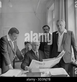 Ein Archivfoto aus dem Jahr 1981 zeigt eine Gruppe von Mitarbeitern der AIZ (Armature-Isolator Plant) in Sloviansk, ukrainische SSR. Fünf Kollegen (vier Männer und eine Frau) sind in einem Büro zu einem politischen Briefing versammelt. Ein leitender Angestellter, der an seinem Schreibtisch sitzt, liest einen artikel aus einer zentralsowjetischen Zeitung, wahrscheinlich "Prawda", während die anderen aufmerksam zuhören. Diese kollektive Lektüre der offiziellen Parteipresse war in der UdSSR eine gängige Praxis. Dies spiegelt die ideologische Seite des Arbeitsalltags im friedlichen Donbass vor dem Krieg wider. Stockfoto
