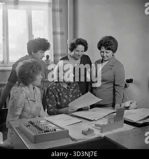 Ein Archivfoto aus dem Jahr 1981 zeigt ein Treffen des Frauenrates (Zhensovet) in der AIZ (Armature-Isolator Plant) in Sloviansk, Ukrainische SSR. Fünf weibliche Angestellte versammeln sich um einen Bürotisch, um zu diskutieren. Die sitzende Frau hält ein Dokument. Auf dem Schreibtisch befinden sich Ordner, ein Drehtelefon und ein traditioneller hölzerner Abacus (schoty). Diese Szene zeigt die administrative und soziale Organisationsarbeit in einer sowjetischen Fabrik. Dies zeigt den Alltag im friedlichen Donbass vor dem Krieg. Stockfoto