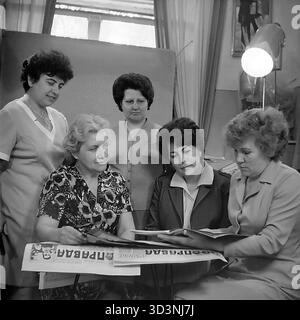 Ein Archivfoto aus dem Jahr 1981 zeigt ein Treffen des Frauenrates (Zhensovet) in der AIZ (Armature-Isolator Plant) in Sloviansk, Ukrainische SSR. Fünf weibliche Angestellte versammeln sich in einem Büro zu einer politischen Diskussion. Sie sitzen um einen Tisch, der mit Kopien der "Prawda", der offiziellen Zeitung der Kommunistischen Partei, bedeckt ist. Die Frauen lesen und diskutieren die Artikel. Diese Szene fängt die Mischung aus sozialer und ideologischer Arbeit innerhalb einer sowjetischen Fabrik ein. Dies zeigt den Alltag im friedlichen Donbass vor dem Krieg. Stockfoto