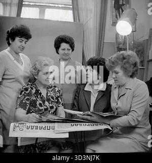 Ein Archivfoto aus dem Jahr 1981 zeigt ein Treffen des Frauenrates (Zhensovet) in der AIZ (Armature-Isolator Plant) in Sloviansk, Ukrainische SSR. Fünf weibliche Angestellte versammeln sich in einem Büro zu einer politischen Diskussion. Sie sitzen um einen Tisch, der mit Kopien der "Prawda", der offiziellen Zeitung der Kommunistischen Partei, bedeckt ist. Die Frauen lesen und diskutieren die Artikel. Diese Szene fängt die Mischung aus sozialer und ideologischer Arbeit innerhalb einer sowjetischen Fabrik ein. Dies zeigt den Alltag im friedlichen Donbass vor dem Krieg. Stockfoto