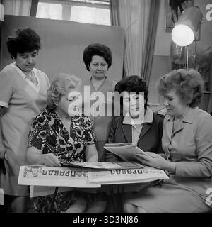 Ein Archivfoto aus dem Jahr 1981 zeigt ein Treffen des Frauenrates (Zhensovet) in der AIZ (Armature-Isolator Plant) in Sloviansk, Ukrainische SSR. Fünf weibliche Angestellte versammeln sich in einem Büro zu einer politischen Diskussion. Sie sitzen um einen Tisch, der mit Kopien der "Prawda", der offiziellen Zeitung der Kommunistischen Partei, bedeckt ist. Die Frauen lesen und diskutieren die Artikel. Diese Szene fängt die Mischung aus sozialer und ideologischer Arbeit innerhalb einer sowjetischen Fabrik ein. Dies zeigt den Alltag im friedlichen Donbass vor dem Krieg. Stockfoto