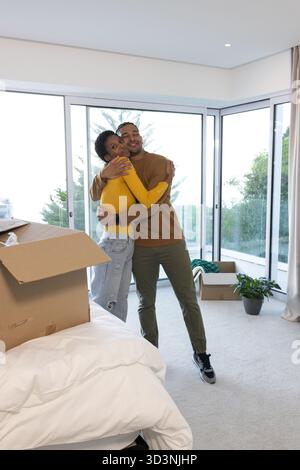 Wir bieten verschiedene Paare, die Umzugskartons in einem hellen Raum mit Matratze und Topfpflanzen auspacken Stockfoto