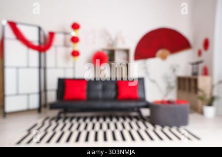 Verschwommener Blick auf das moderne Wohnzimmer mit schwarzem Sofa und Dekoration für das chinesische Neujahrsfest Stockfoto