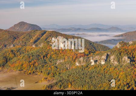 panoramablick auf farbenprächtiges Herbstlaub, das eine bergige Landschaft bedeckt, mit nebeligen Tälern, die in der Ferne sichtbar sind. Die Sulov Rocks, National n Stockfoto