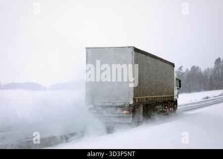 Semi-Truck fährt an einem Tag mit starkem Schneefall im Januar auf der verschneiten Autobahn. Schwierige Straßenverhältnisse. Rückansicht, Kopierraum. Stockfoto